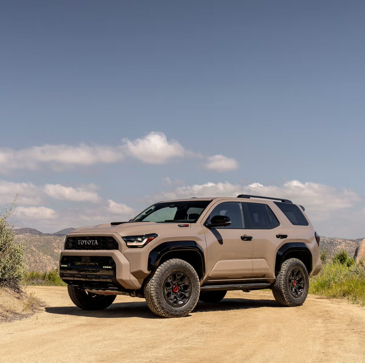 New 6th gen Toyota 4Runner on a trail with beautiful mountains in the distance.