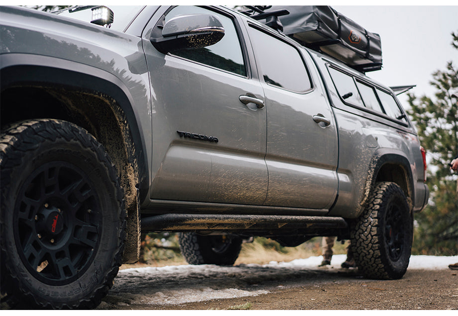 Modified 2012 Toyota Tacoma 2nd Gen with lift kit and roof rack on dirt trail.