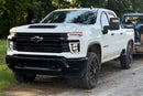 White Chevrolet Silverado HD with Morimoto Chevrolet Silverado HD (20-24) XB LED Headlights on a dirt road with trees in the background