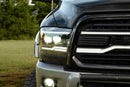 Close-up of a truck's front grille and headlights with a blurred natural background