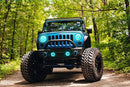 Front end of a Jeep Wrangler JK with cyan LED headlight and fog light halos installed.
