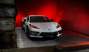Three quarters view of a white C8 Corvette with red headlight DRLs.