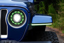 Close-up of a blue Jeep Wrangler's headlight with green accents on a natural background