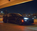 Three quarters view of a black Chevrolet Camaro with white headlight and fog light DRLs.