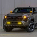 Toyota Tacoma truck with illuminated FORM Lighting fog lights in front of a plain background.