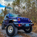 Three quarters view of a blue Jeep Wrangler JL, with ColorSHIFT Oculus Headlights installed, and red halos on.
