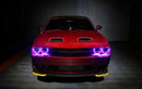 Front view of a red Dodge Challenger with pink LED headlight halo rings installed.