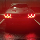 Front end of a Dodge Challenger with red LED headlight halo rings installed.