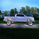 Side view of a white truck with white wheel rings and rock lights.