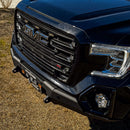 Close-up of a GMC truck's front grille and headlight on a textured surface.