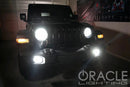 Black Jeep in a garage with very bright headlights and fog lights.