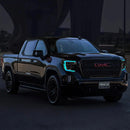 Three quarters view of a black GMC Sierra with cyan headlight DRLs.