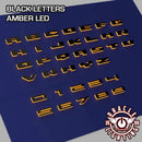 Amber LED Illuminated Letter Badges with Matte Black finish.