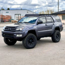 Gray SUV with large tires and a prinsu roof rack on a paved surface.