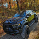A black RAM TRX driving on a trail outdoors, with multiple ORACLE Lighting products installed, including LED Off-Road Side Mirror Ditch Lights, and Front Bumper Integrated Light Bar.