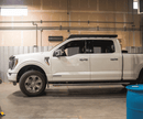 White Ford F150 pickup truck with a prinsu pro roof rack in a warehouse setting