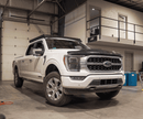 White Ford F150 pickup truck parked inside a warehouse with a black prinsu pro roof rack mounted on top.