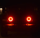 Jeep in the dark with only red halo headlights being visible