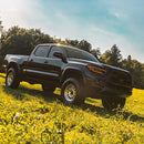 Black pickup truck in a grassy field with trees in the background