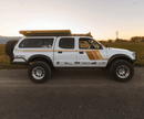 White off-road toyota tacoma with a prinsu pro roof rack and additional equipment on a road at sunset