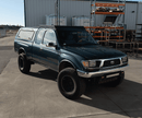 Blue Toyota truck parked in a lot with industrial background